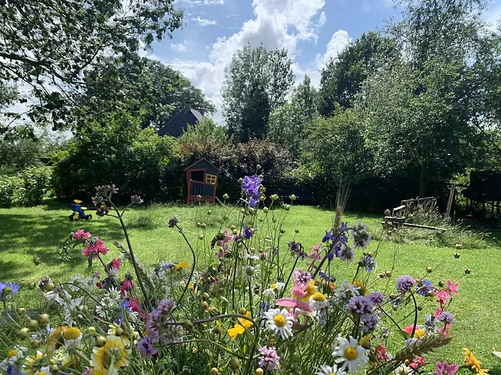 De bloementuin met wilde bloemen en het speelhuisje van De Tuin van Meta