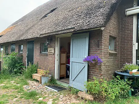De voordeur van de boerderij met bloemen ernaast