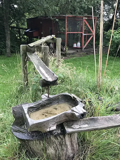 Een houten watergoot en een uitgeholde boomstam om mee te spelen in de tuin